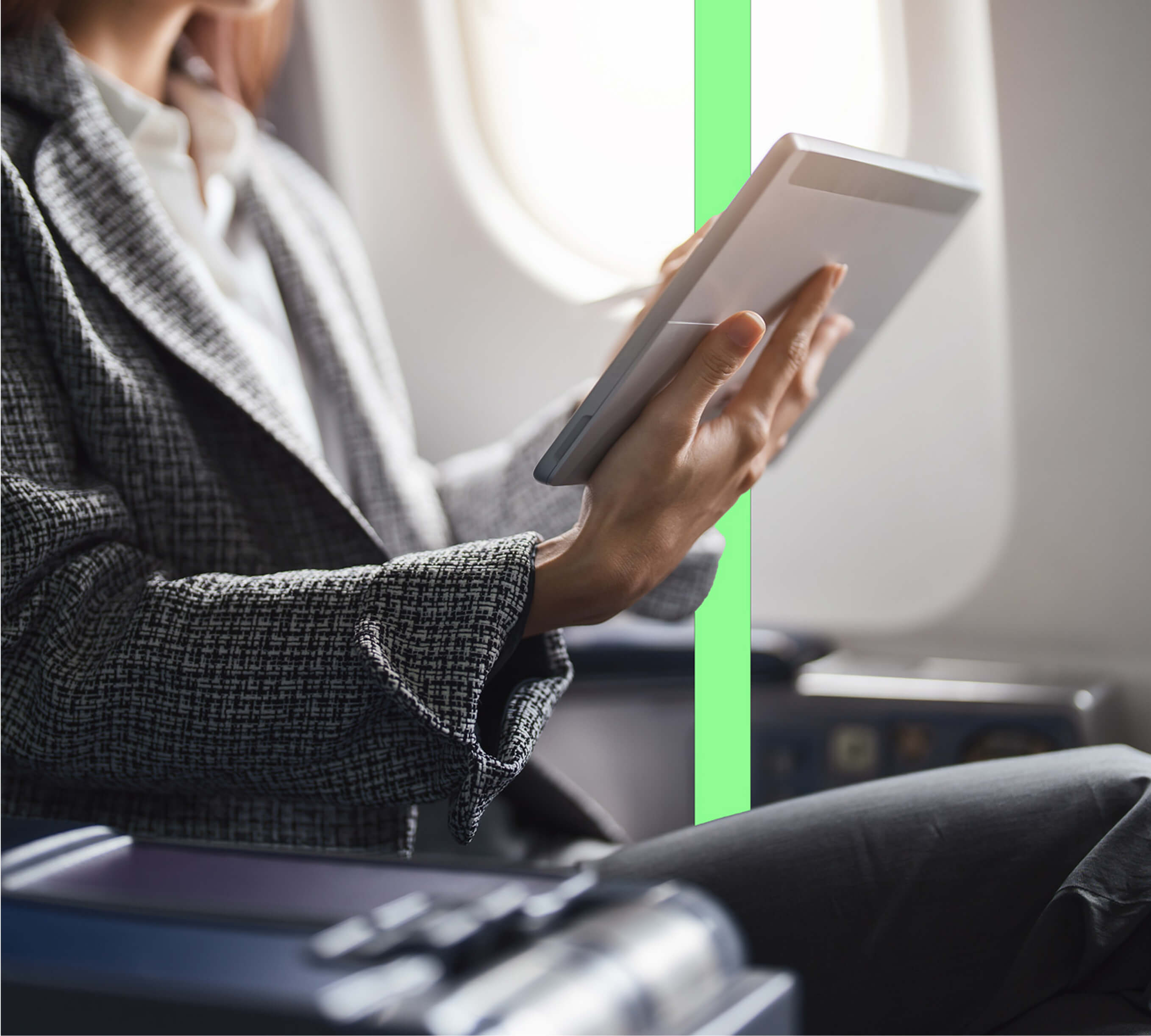 A woman in a suit holding a tablet in an aeroplane seat.